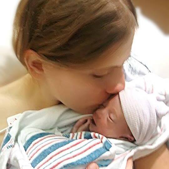 mom kissing newborn baby