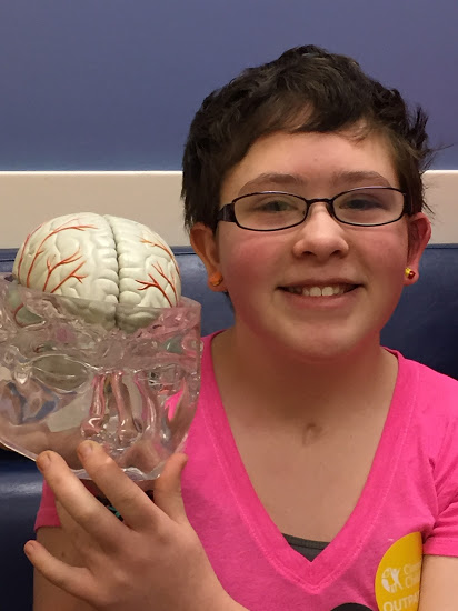 Amelia smiling holding a model of a brain