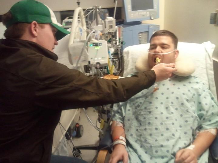 a man feeding his friend in the hospital after surgery