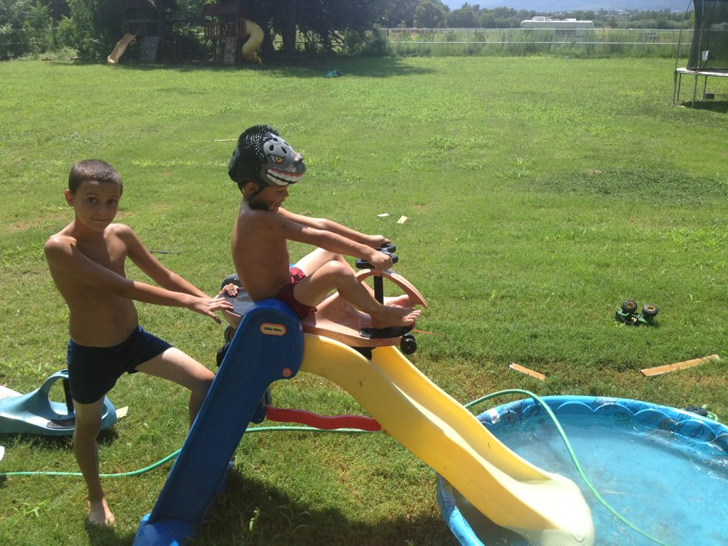 sons about to go down a slide on a scooter