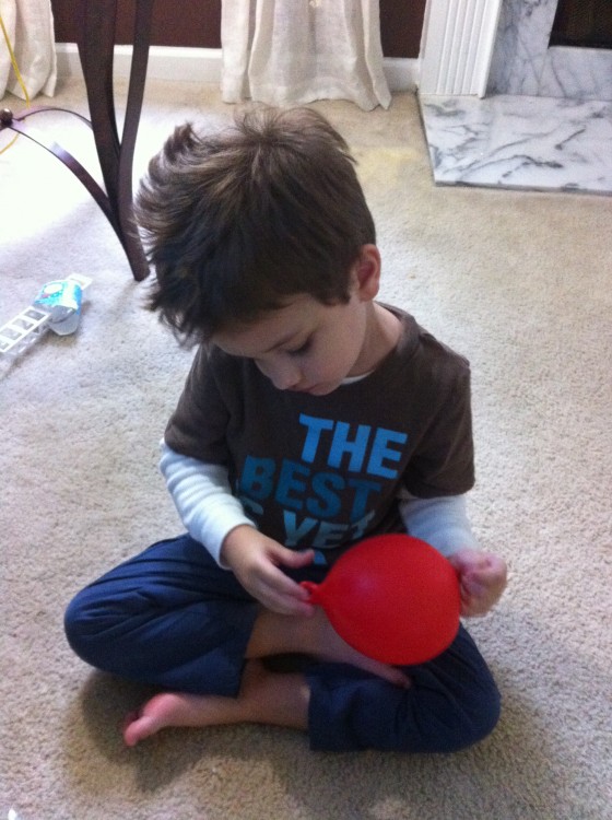 young boy playing with a red balloon