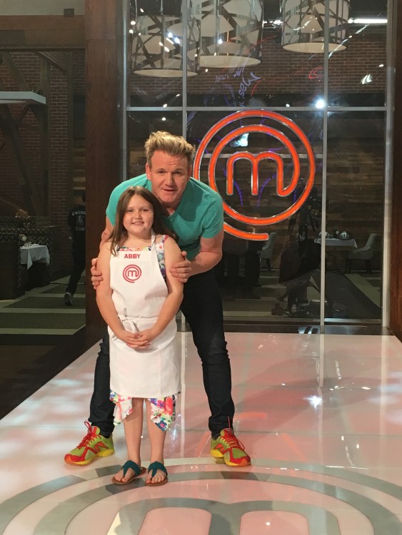 Gordon Ramsay standing behind Abby on the set.