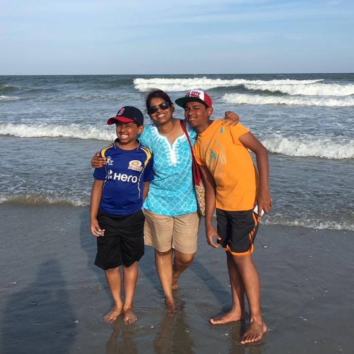 woman with two boys standing on the beach
