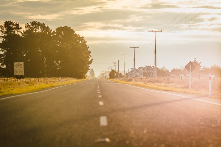 a road going through farmland at sunrise