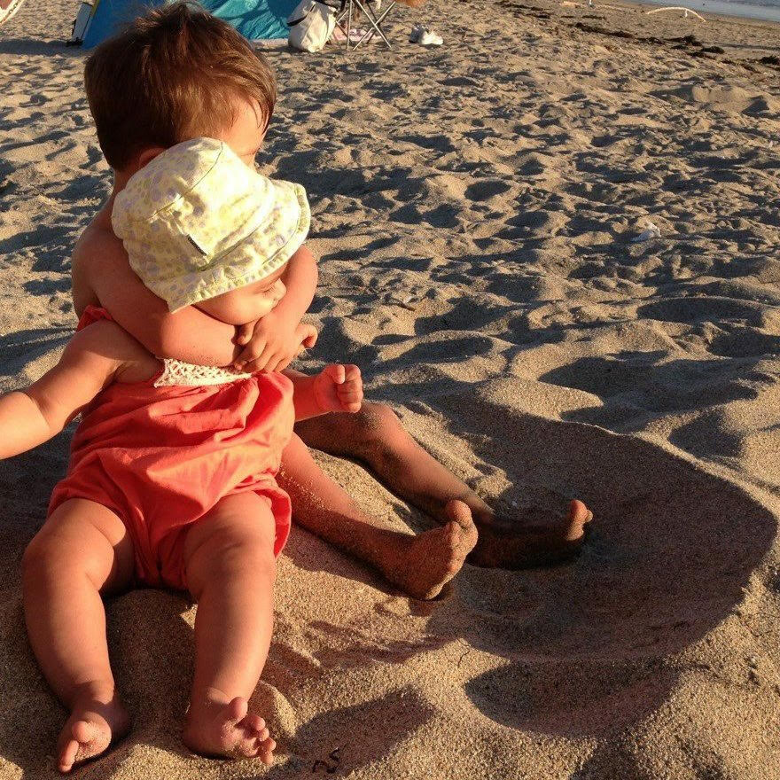 brother hugging baby sister on the beach