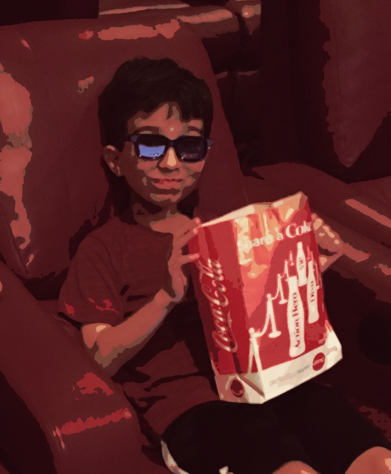 little boy with popcorn in lap at the movies