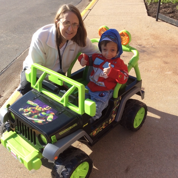 Arshaan with his physical therapist in a jeep she made outside