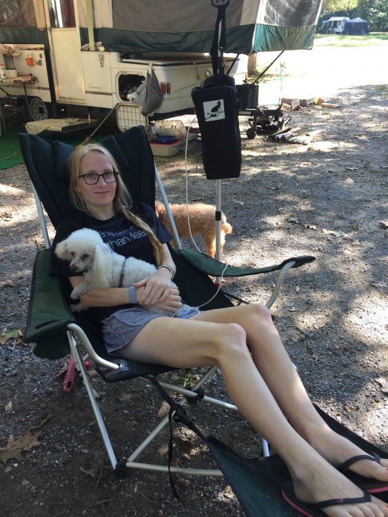 girl sitting at campsite getting tube feeding