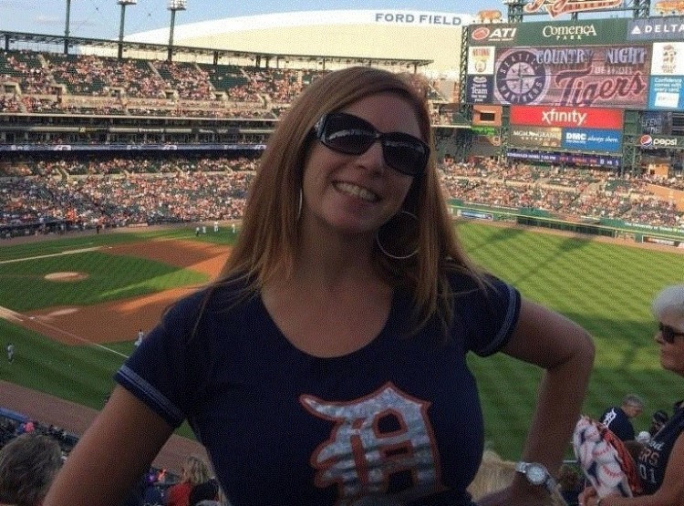 woman standing in baseball stadium with field behind her
