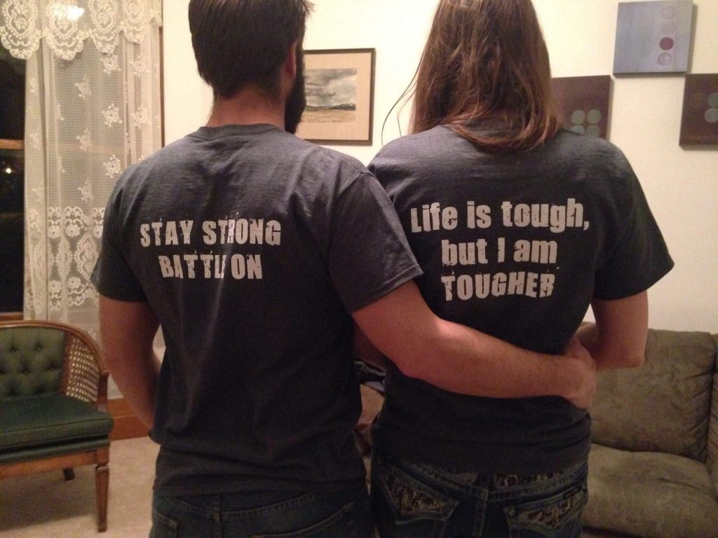 husband and wife wearing t-shirts that say 'stay strong, battle on' and 'life is tough, but I am tougher'