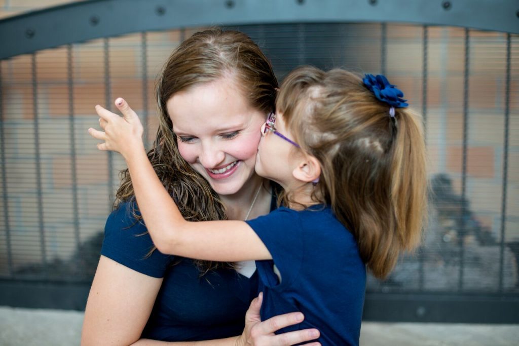 young daughter kissing her mother on the cheek