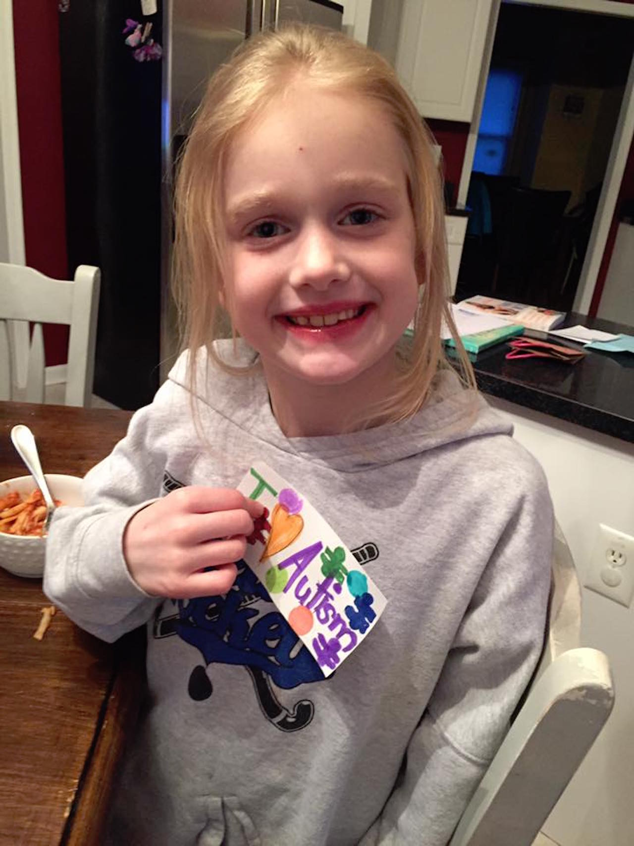 little girl holding sign that says i love autism