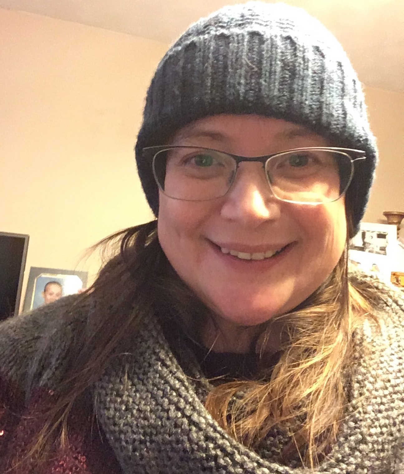 Woman smiling, wearing a beanie and glasses