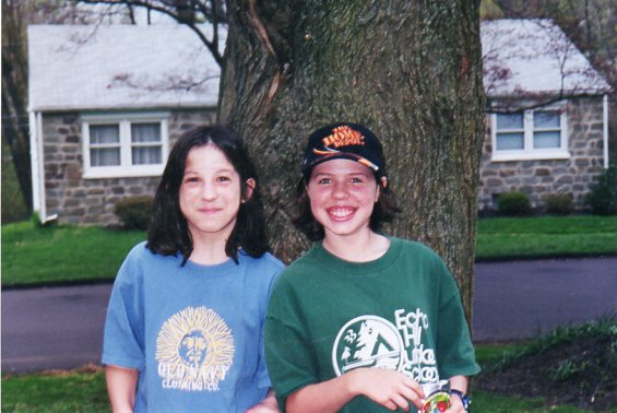 The author and her friend as kids, posting outdoors in front of tree in neighborhood