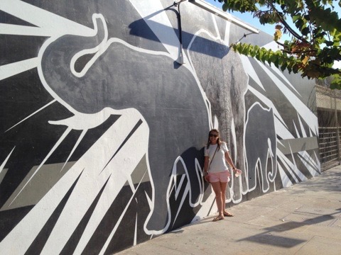 girl standing next to painting of elephants