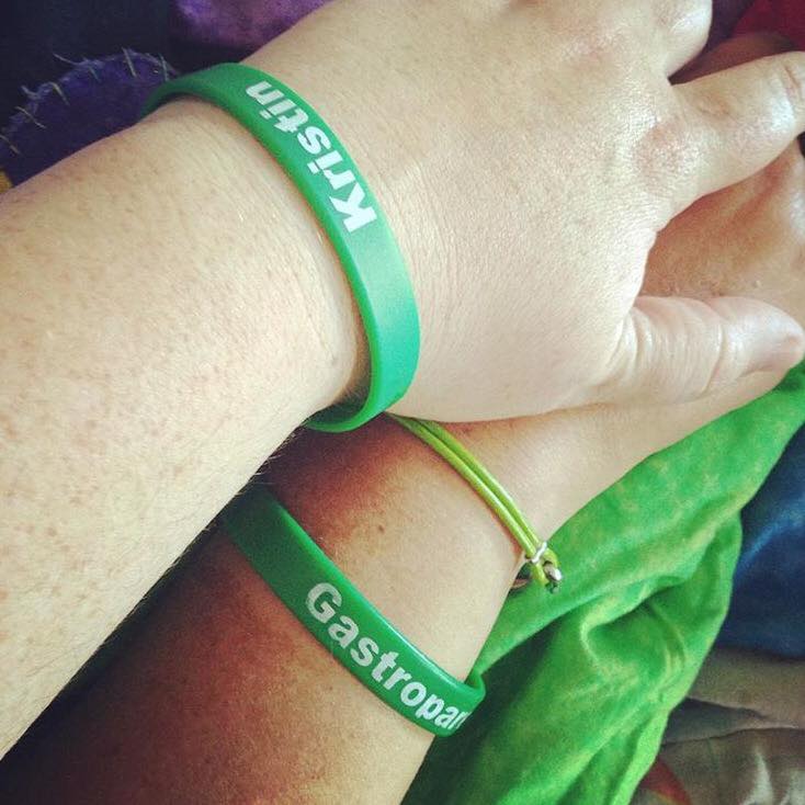 two hands wearing green gastroparesis bracelets