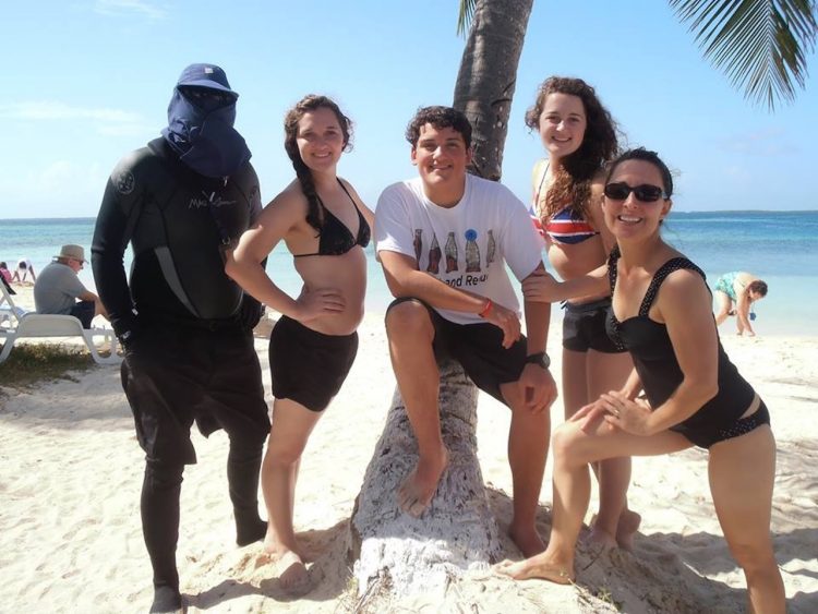 man wearing wetsuit standing on beach with his adult children