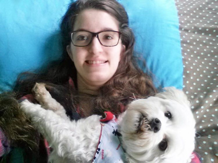 girl holding small white dog on lap