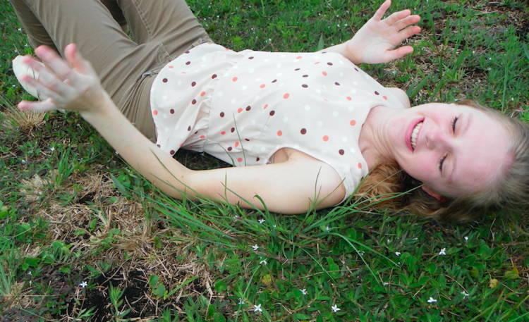 teenage girl lying in the grass and laughing