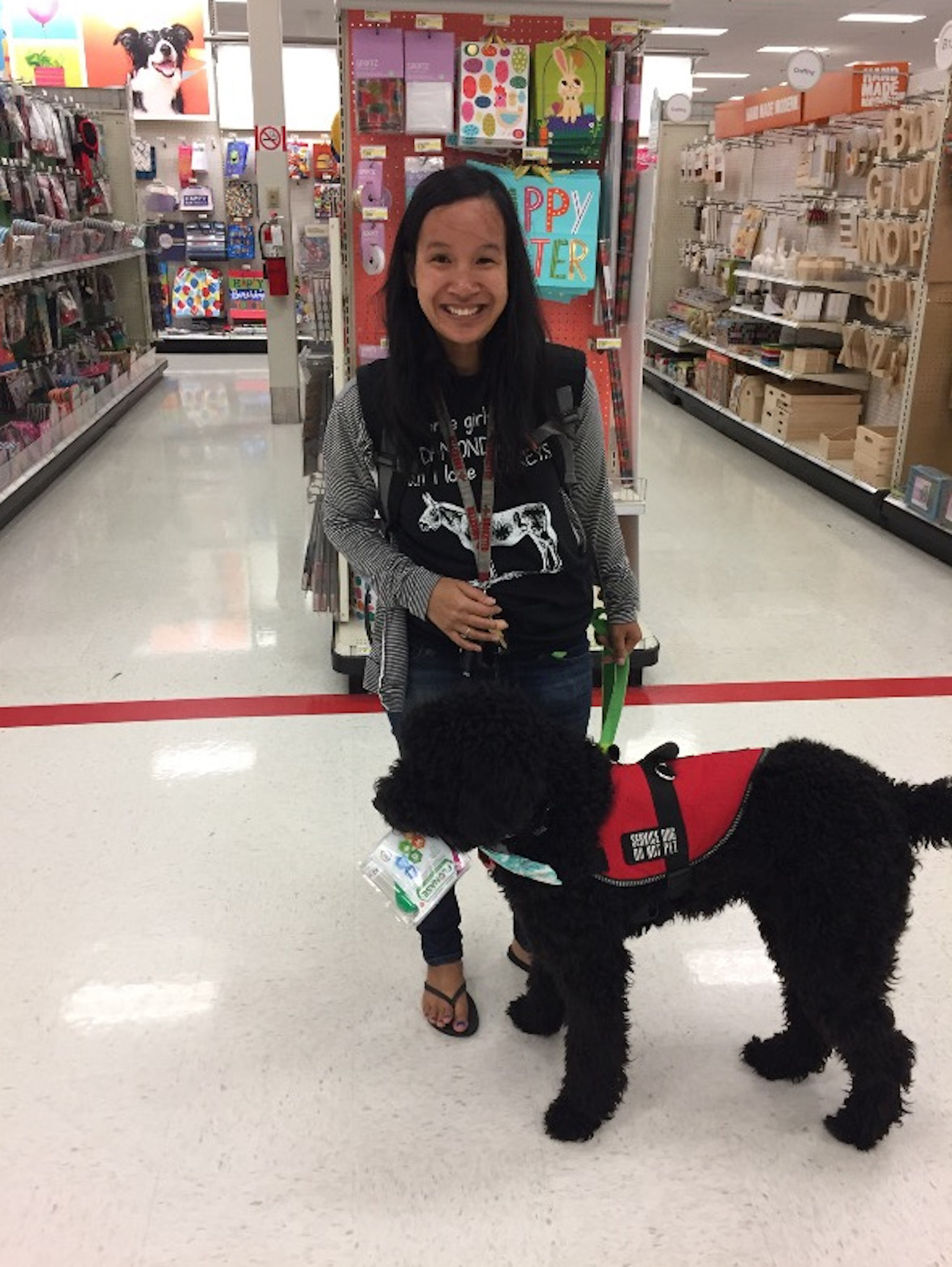 Sara with her service dog Rufus in front of a store aisle