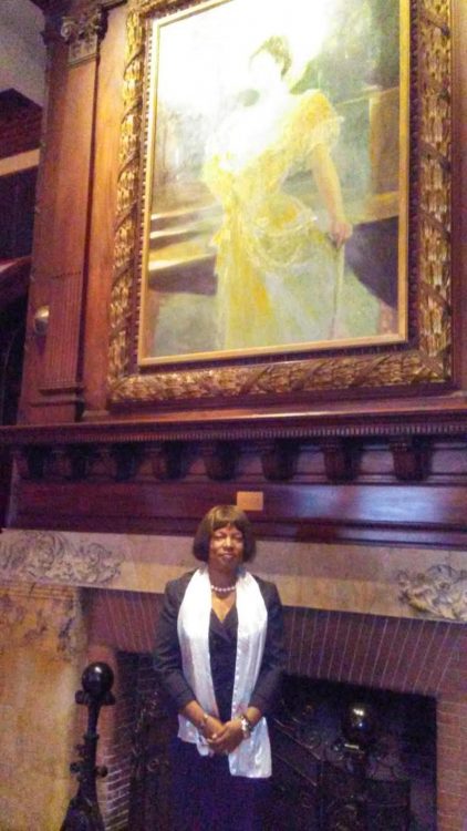 woman posing in front of a large framed painting over a fireplace