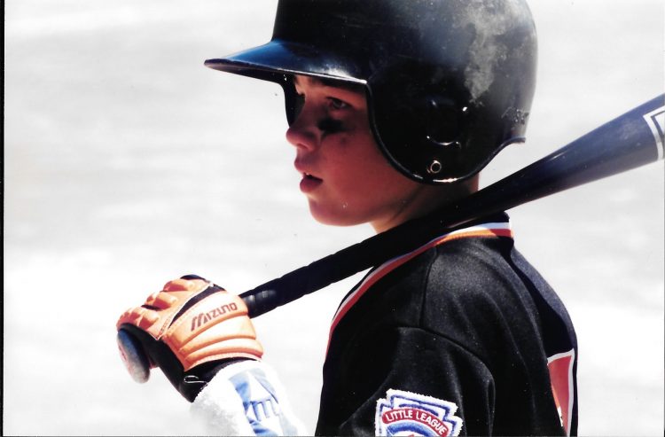 boy wearing baseball helmet and holding baseball bat