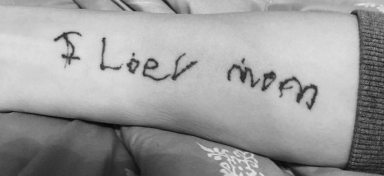 arm with tattoo that says in child's writing i loev mom