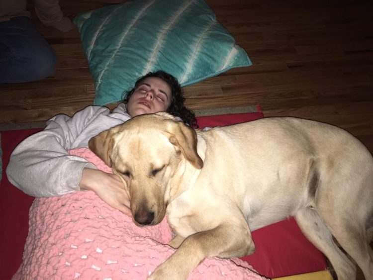girl lying on floor with dog snuggling her