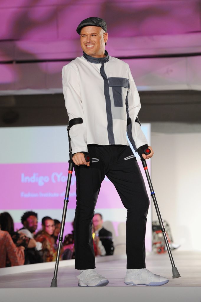 A model walks the runway with crutches, showcasing a design.