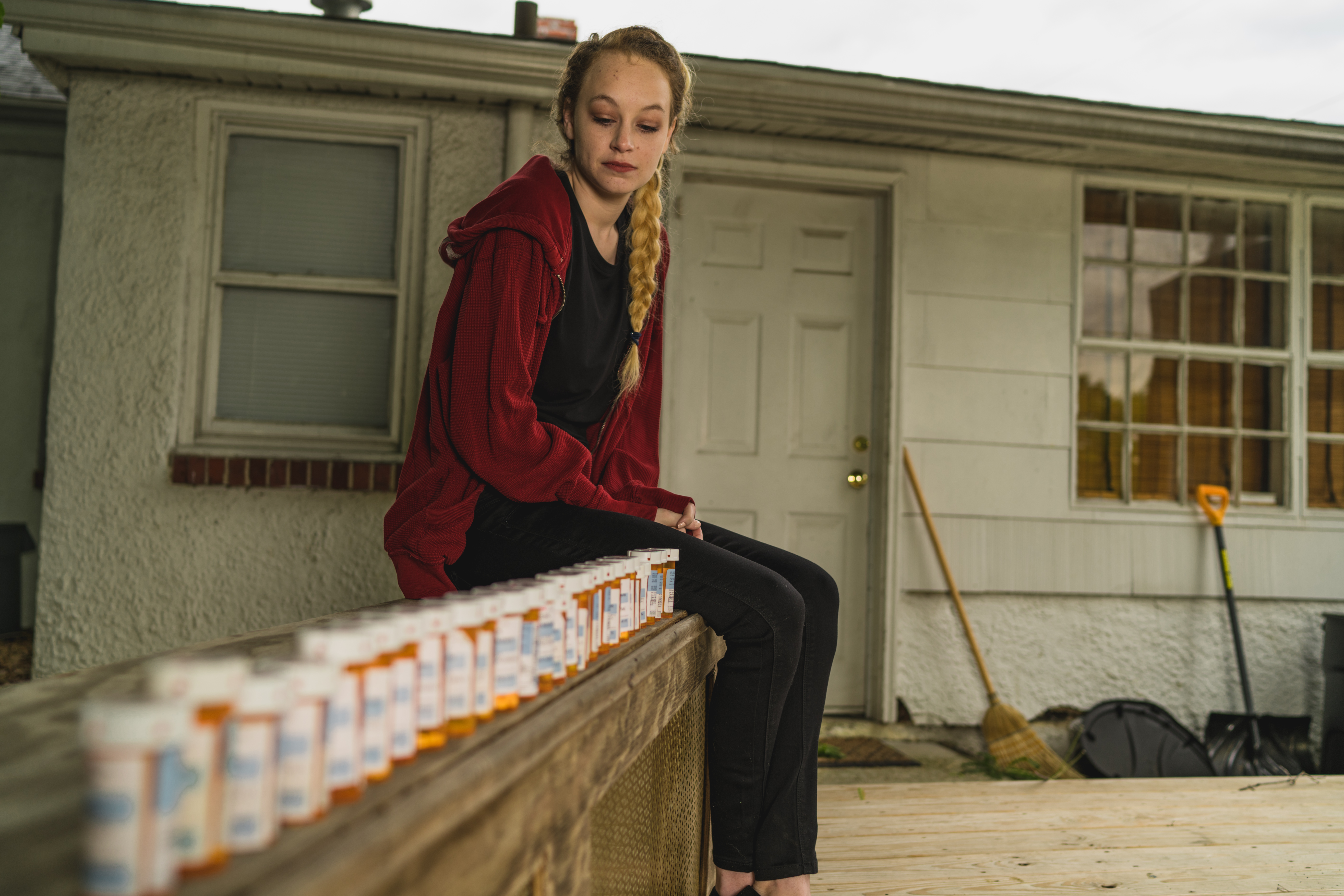 wide shot of woman on bench with medication bottles