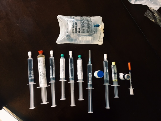 row of needles, injections and bag of iv fluids