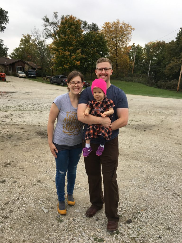 parents holding their young daughter outside