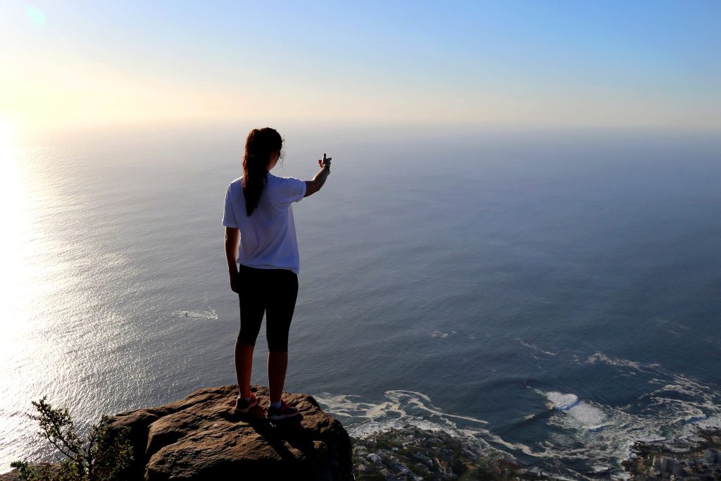 woman standing on a cliff overlooking the ocean