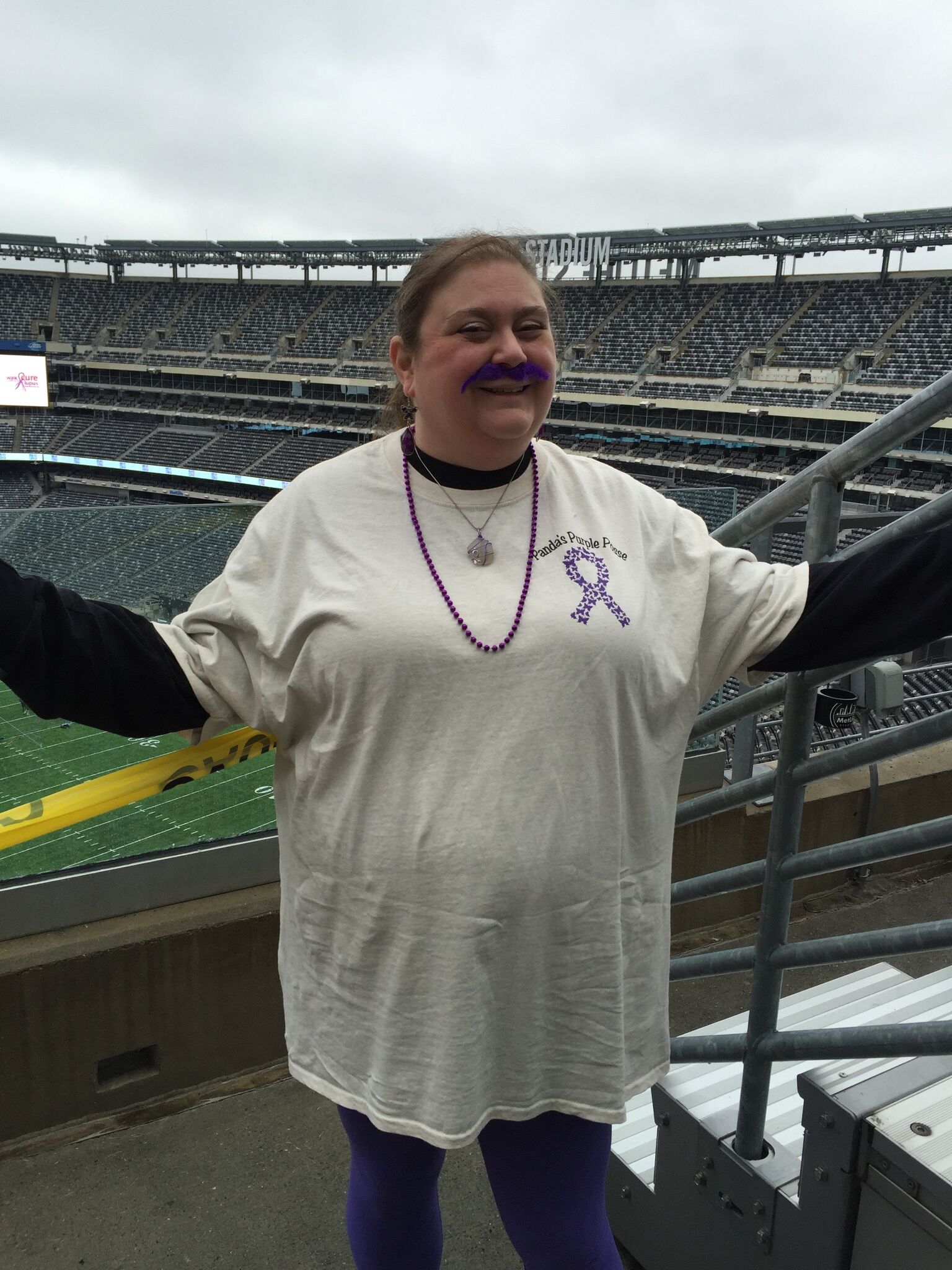 woman wearing a lupus awareness tshirt and standing in a baseball stadium