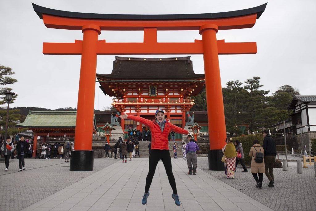 woman in front of japanese shrine jumping for joy