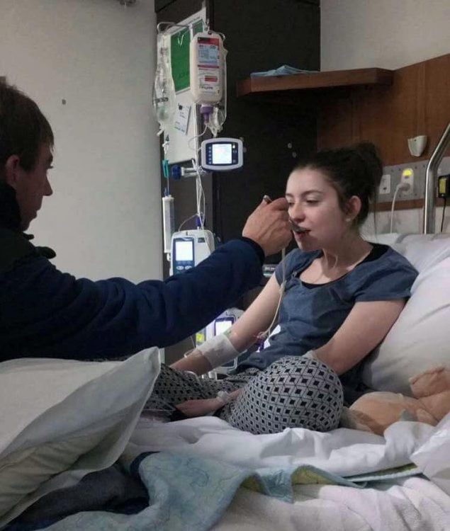dad spoon-feeding his daughter in the hospital