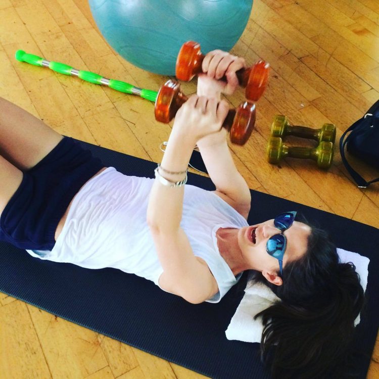 woman lying on the ground and lifting weights in physical therapy