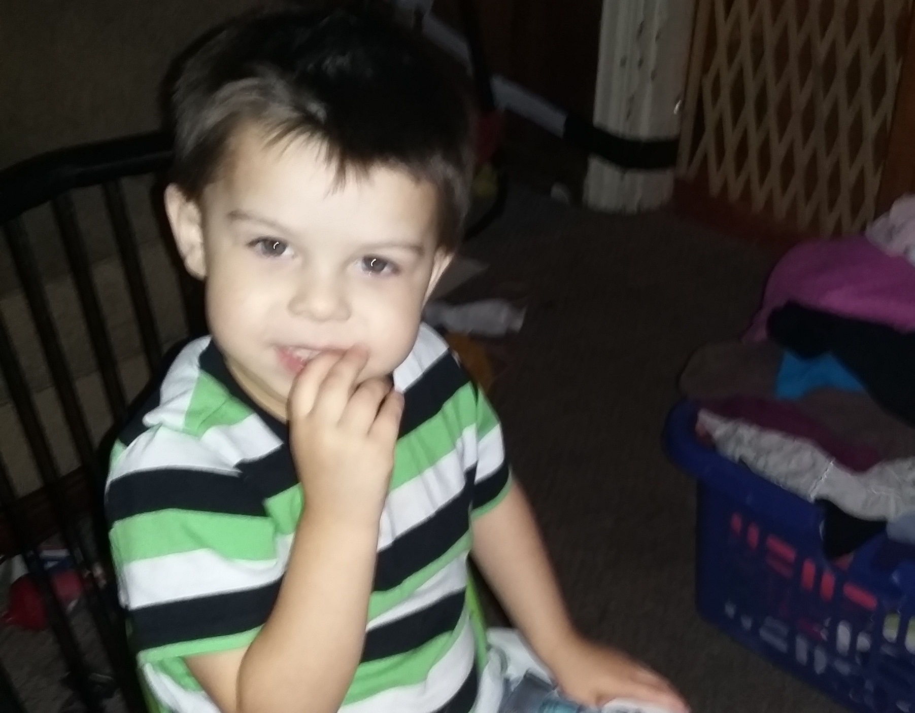 Boy wearing a striped shirt, sitting in a chair indoors