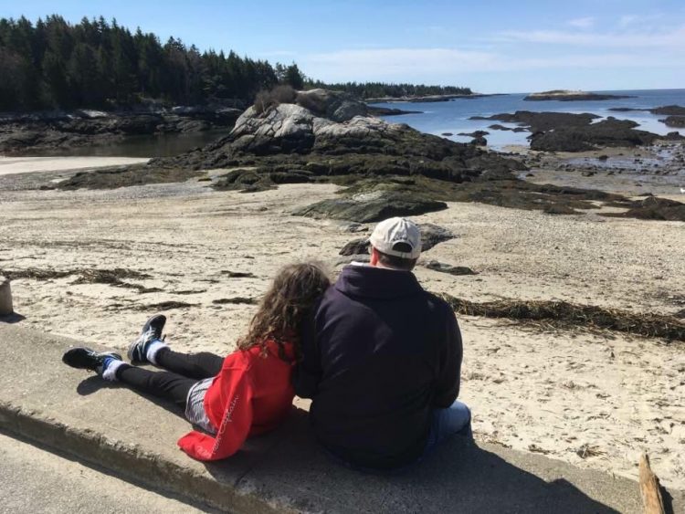dad supporting daughter next to the beach