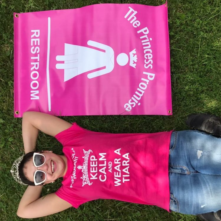 woman lying on the ground in a pink shirt next to a pink banner with the princess promise logo