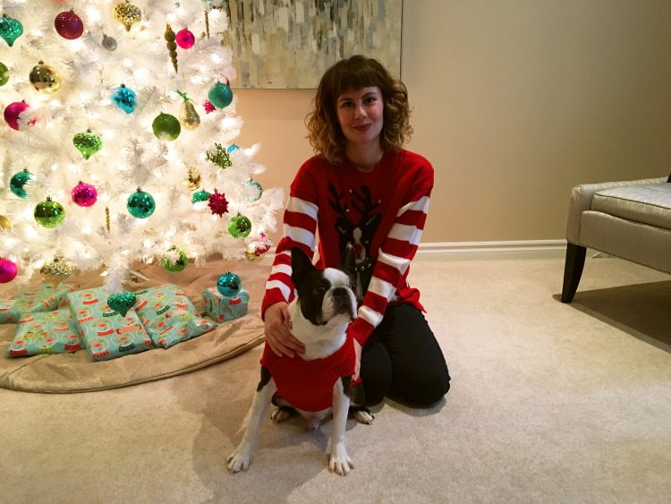 woman posing with her boston terrier in front of a christmas tree