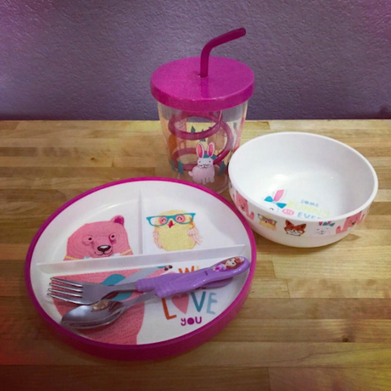 Child's plate with illustrations of animals on it, plus matching bowl, cup with a straw and eating utensils