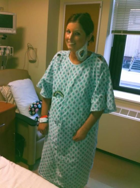 woman smiling in a hospital gown with an IV in her neck