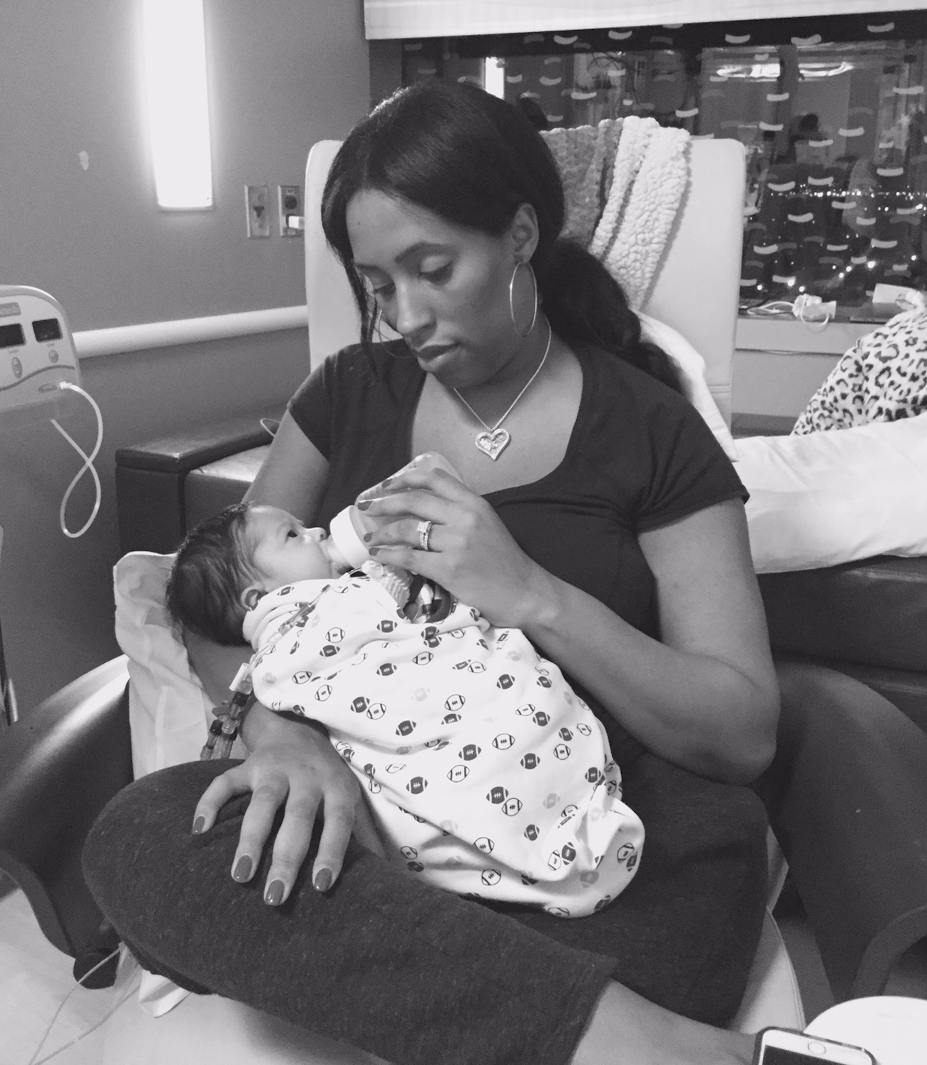 Mother holding her baby, giving her baby a bottle in a hospital room