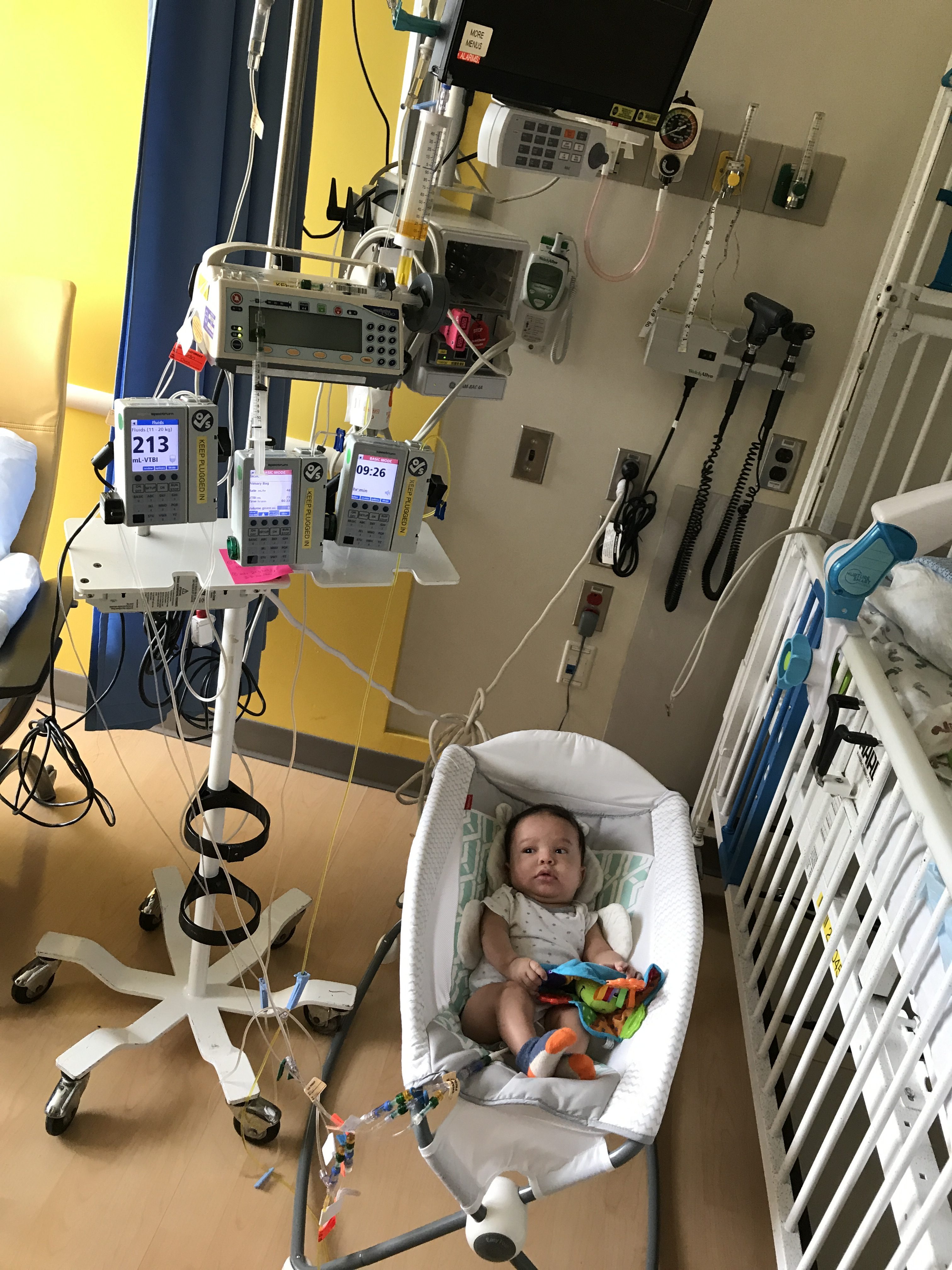 baby in bassinet next to crib in hospital