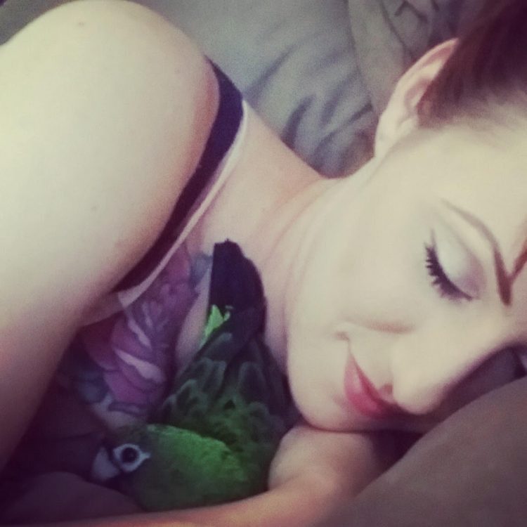woman cuddling with her parrot