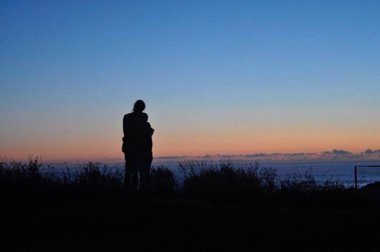 silhouette of a couple hugging in front of the ocean at dusk