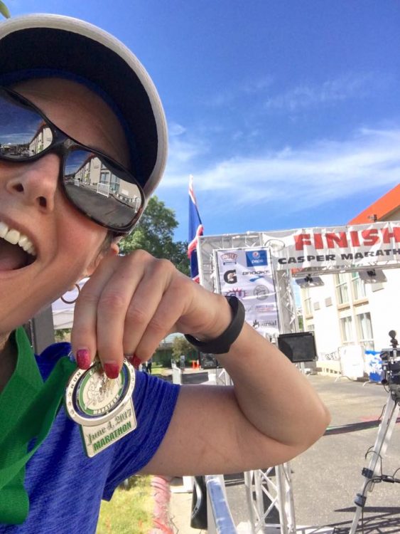 woman holding a medal after running a half-marathon