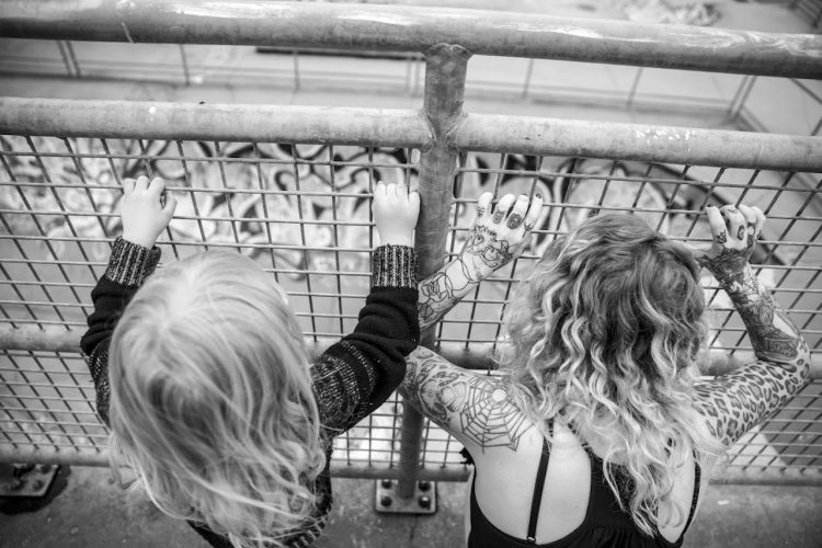 black and white photo of mother and son looking through wire fence