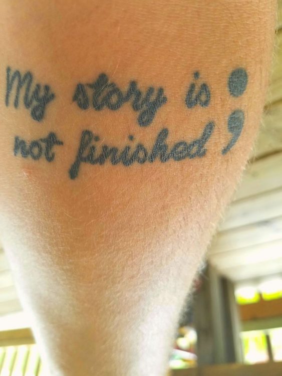 man with tattoo on his arm that says 'my story is not finished'